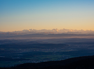 Swiss horizon during corona-virus COVID-19 pandemic with great visibility over a Central Valley or Flatland on Alps mountains from Jura mountains in canton Basel-Land at colorful sunset.