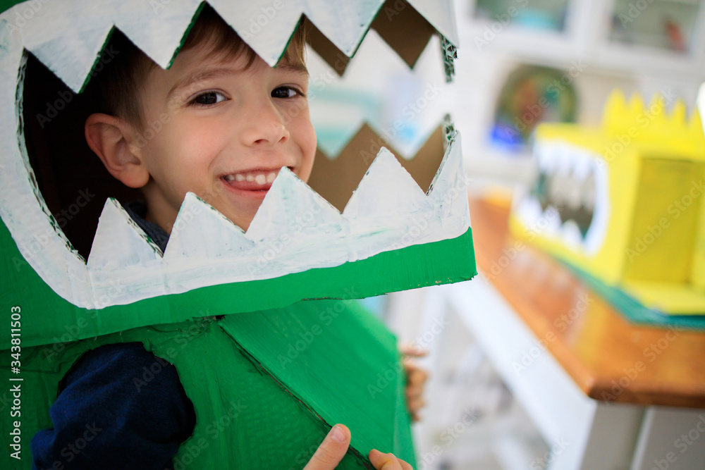 Wall mural Smiling boy wearing a cardboard dinosaur costume