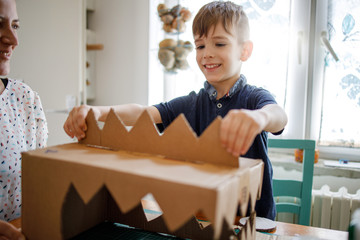 Smiling boy making  a cardboard dinosaur costume