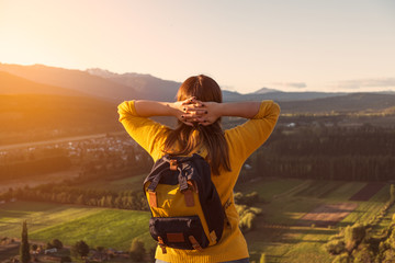 A relaxed young woman staring at landscape with her arms behind her neck