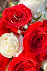 wedding bouquet of white and red roses, wedding rings of the bride and groom