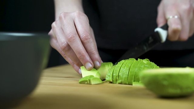 Las manos de una chica trocean la mitad de un aguacate.
