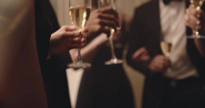 Multi-ethnic friends drinking wine at a party. Group of men and women raise their glasses for a toast at new years party.

