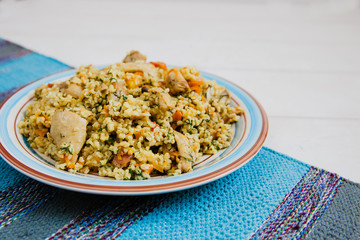 Uzbek pilaf with chicken on the blue striped mat lying on a white background.