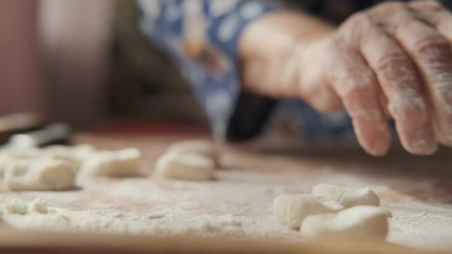 Elderly woman is preparing pastry dish; wrinkled hands in flour