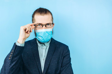 a successful muschin in a suit, glasses and a medical mask on a blue background. Businessman. A private entrepreneur affected by the coronavirus epidemic. Pandemic covid 2019.