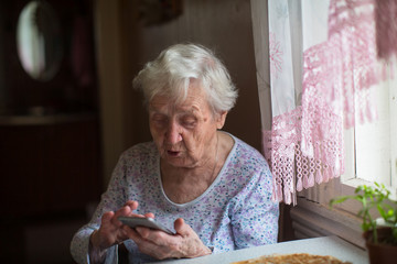 Very old woman use a smartphone in home.