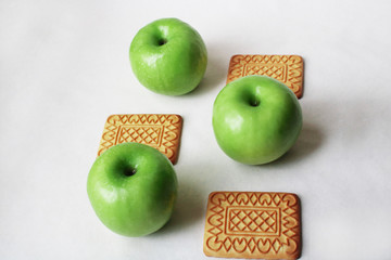 cookies and three green apples on a white background