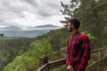 Naklejka premium dark-haired man in a plaid shirt in a viewpoint of a national park