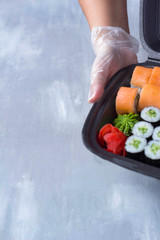 sushi delivery, home delivery in plastic and paper packaging, contactless delivery during the coronavirus epidemic, place for text
