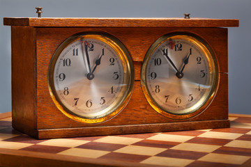 Old wooden vintage chess clock and a chessboard 