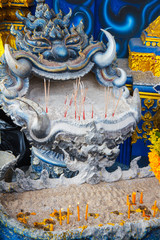 incense sticks and candles in sand at the entrance to the blue temple in Thailand, Chiang rai