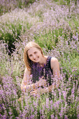 Beautiful girl in dress in purple lavender field. Girl collect lavender. Enjoy the floral glade, summer nature. Natural cosmetics and eco makeup concept.
