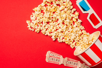Top view of popcorn, cinema tickets and 3d glasses on red background