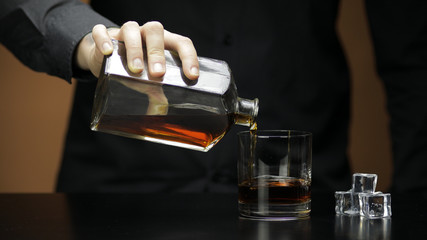 Pouring whiskey, cognac into glass. Bartender pours alcohol drink. Silhouette