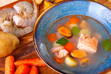 soup in a plate and ingredients included in it on a wooden board