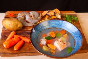 soup in a plate and ingredients included in it on a wooden board