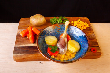soup in a plate and ingredients included in it on a wooden board