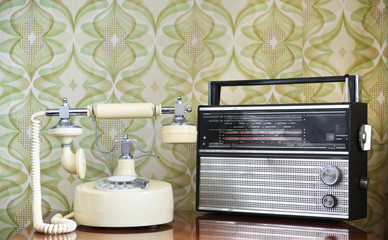 Retro radio on the table against the background of vintage wallpaper