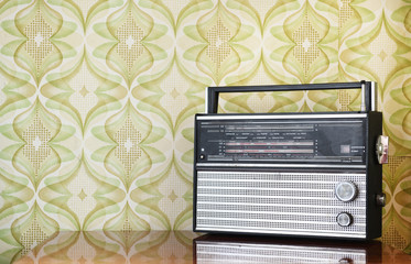 Retro radio on the table against the background of vintage wallpaper	