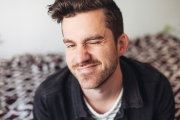 Fototapeta premium A portrait of a young handsome man wink, indoors