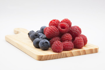 blueberries and raspberries in a wooden board