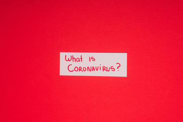 Top view of card with what is coronavirus lettering isolated on red
