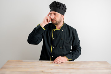 Young male chef in black uniform wondering