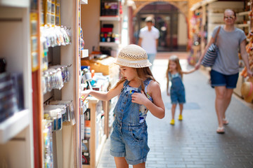 little girl chooses Souvenirs in street shop hotel