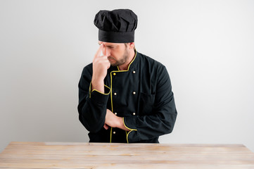 Young male chef in black uniform wondering