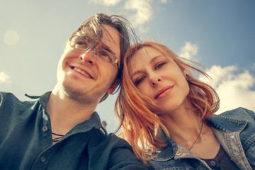 Happy young couple posing for selfie on a sunny day outside.