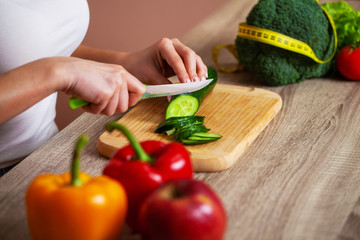 Closeup of woman slices cucumber for fresh salad