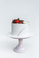 A beautiful white cake with cheese cream, meringues, chocolate and fresh Berries on a white background. The original idea for a wedding cake or birthday cake.
