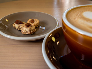 cookies with nuts are on a gray plate and a Cup of coffee are on a wooden table.