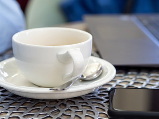 empty coffee Cup are on the table in the cafe. laptop and smartphone in the background. close up. copy space