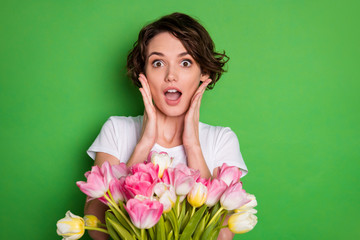 Clloseup photo of beautiful cute lady wavy hairdo receiving large big tulips surprise bunch present secret admirer delivery service wear casual white t-shirt isolated green color background
