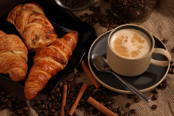 Ceramic Cup with coffee, cinnamon, and mouth-watering cakes on burlap
