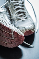 Old dirty sneakers close up, selective focus, desaturated colors.