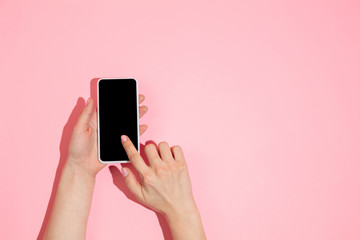 Hand using gadget, smartphone on top view, blank screen with copyspace, minimalistic style. Technologies, modern, marketing. Negative space for advertising. Coral color on background. Stylish, trendy.