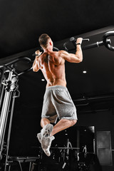 Bodybuilder does pull-ups. Muscular man in the gym. Preparation for competitions, functional training. The athlete is gaining his form.