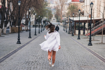 girl or woman in a white medical coat runs away along the street. doctor, nurse runs around the city. coronavirus, disease, infection, quarantine, covid-19