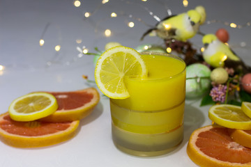 Glass with orange juice, slices of lemon, slices of grapefruit with a beautiful background on a white table