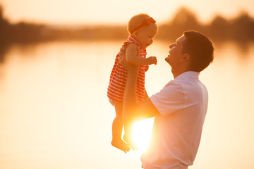 Young happy father holding and embracing his little baby. Dad and his child on sunset.