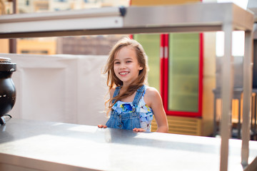 little girl behind an empty counter, serving table