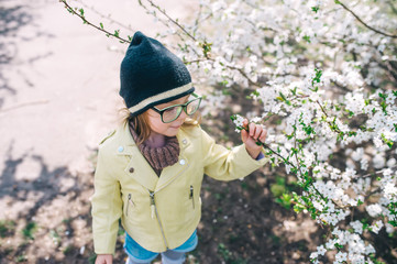 Little girl in sunglasses having fun in apple spring garden. Top view