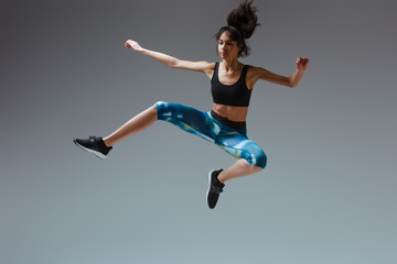 african american girl in sportswear jumping on grey