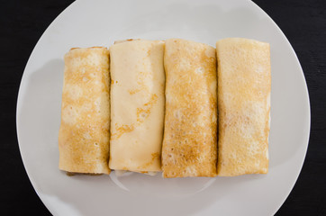 tasty pancakes with cottage cheese in a white plate isolated on a black background.