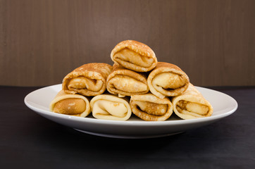 tasty pancakes with cottage cheese in a white plate on a black background. Side view.