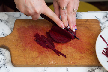Woman is cutting a beetroot to prepare dish for family