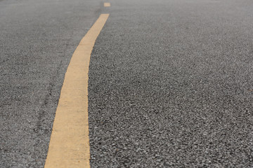 Fototapeta premium Yellow paint line on old asphalt bend